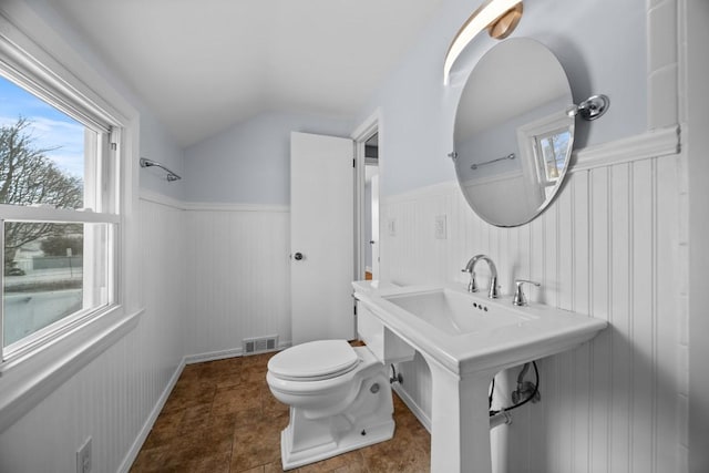 bathroom with plenty of natural light, walk in shower, toilet, and lofted ceiling