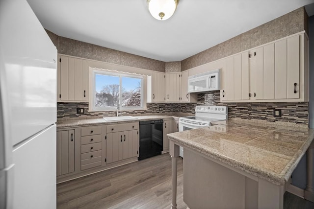 kitchen featuring light hardwood / wood-style flooring, white appliances, sink, a kitchen bar, and kitchen peninsula