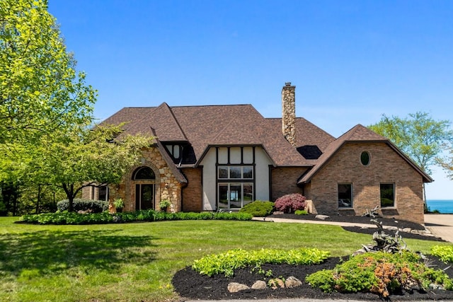 100 Fox Hollow Ln, Harborcreek, PA 16511 - tudor home featuring a front lawn, a chimney, stone siding, and brick siding