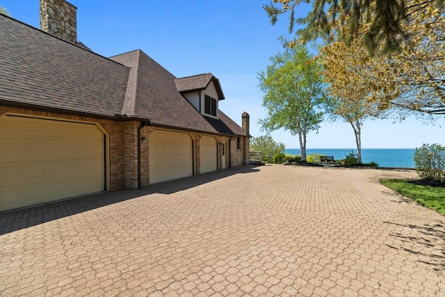 100 Fox Hollow Ln, Harborcreek, PA 16511 - view of side of property featuring brick siding, a water view, driveway, roof with shingles, and a garage