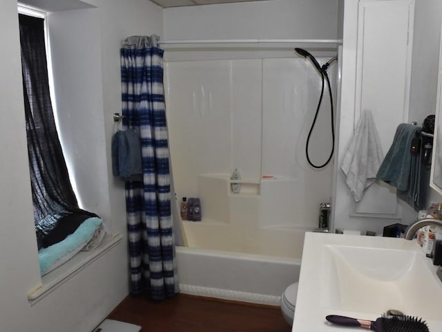 bathroom with a sink, toilet, wood finished floors, and shower / bath combo