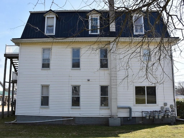 rear view of house featuring mansard roof