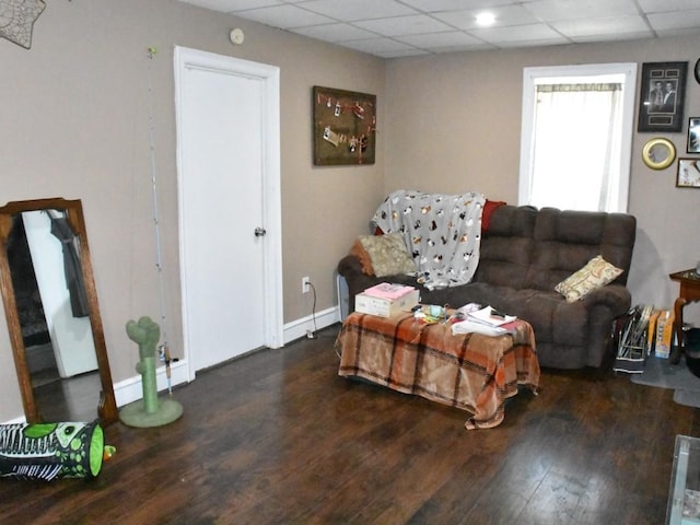 living room featuring wood finished floors, baseboards, and a paneled ceiling