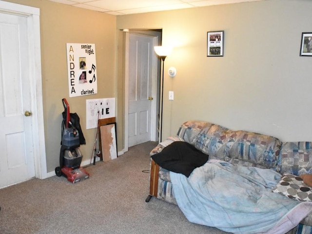 living room featuring a drop ceiling and carpet flooring