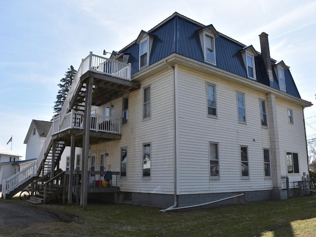 view of property exterior with stairway, metal roof, and a chimney