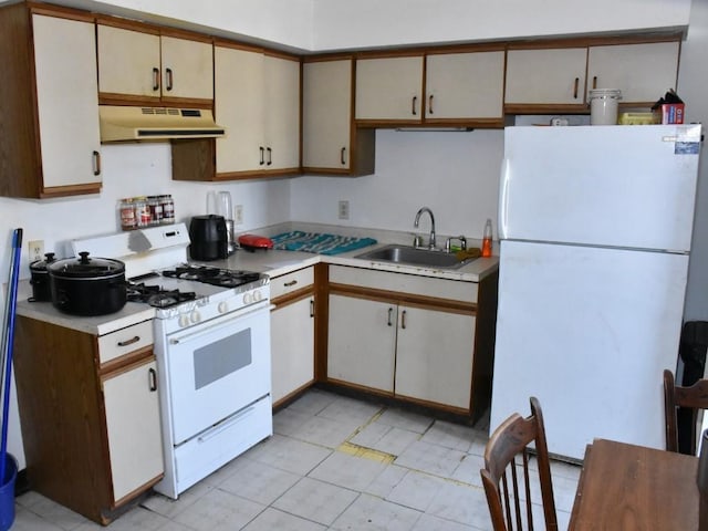 kitchen featuring under cabinet range hood, white appliances, light countertops, and a sink