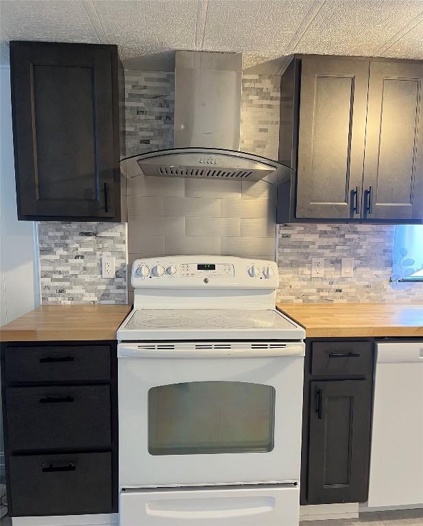 kitchen featuring decorative backsplash, wall chimney exhaust hood, white appliances, and wood counters