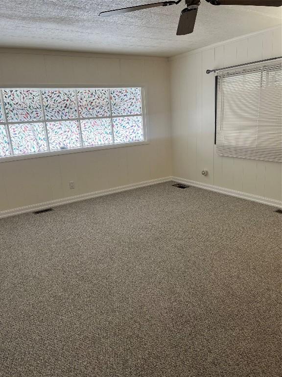 carpeted spare room featuring ceiling fan and a textured ceiling