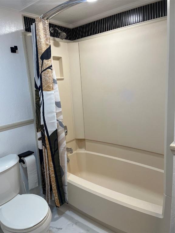 bathroom featuring ornamental molding, toilet, and shower / bath combo with shower curtain