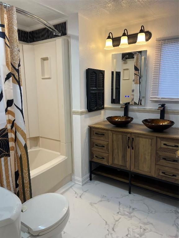 full bathroom with vanity, shower / bath combination with curtain, a textured ceiling, and toilet