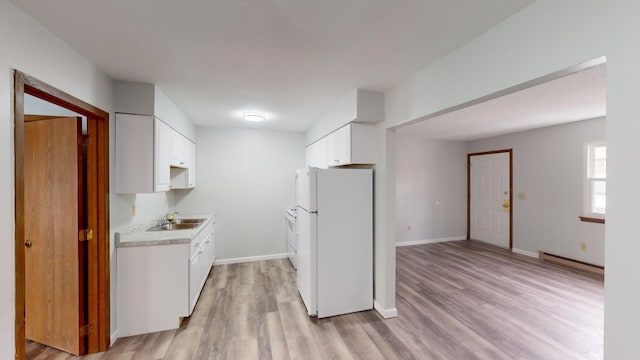 kitchen featuring a baseboard heating unit, white fridge, sink, and white cabinets