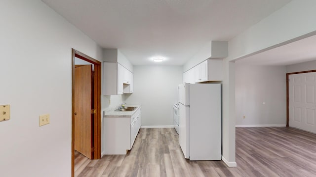 kitchen featuring white fridge, sink, white cabinets, and light hardwood / wood-style flooring