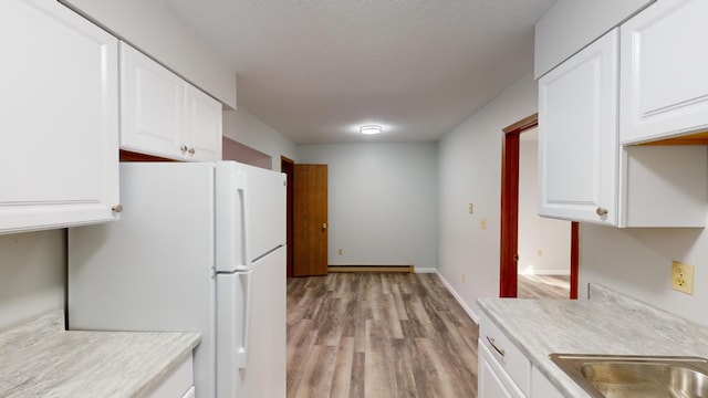 kitchen featuring white refrigerator, white cabinetry, light hardwood / wood-style flooring, and a baseboard heating unit