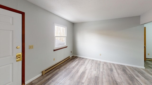 empty room with a baseboard heating unit, a textured ceiling, and light wood-type flooring