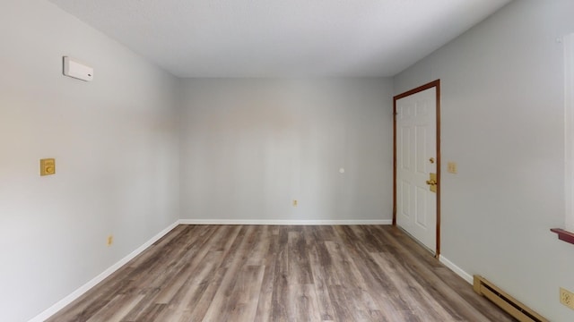 spare room with wood-type flooring and a baseboard heating unit