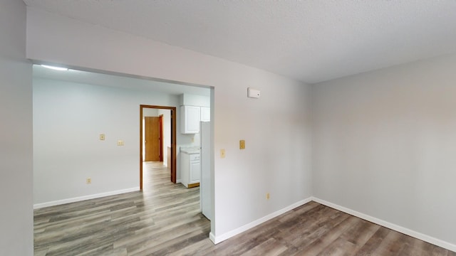 unfurnished room with wood-type flooring and a textured ceiling