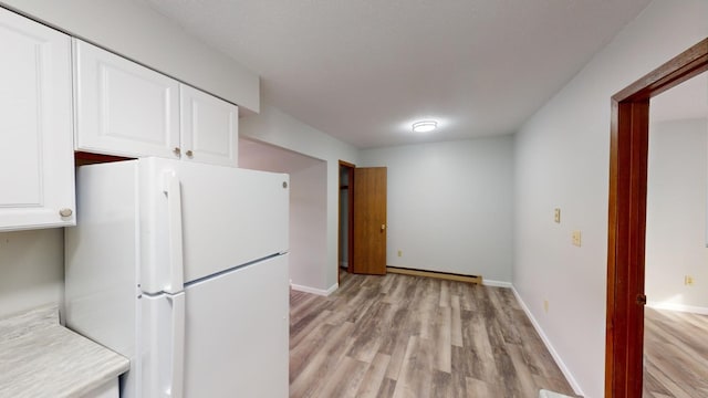 kitchen featuring white cabinetry, light wood-type flooring, white fridge, and a baseboard heating unit