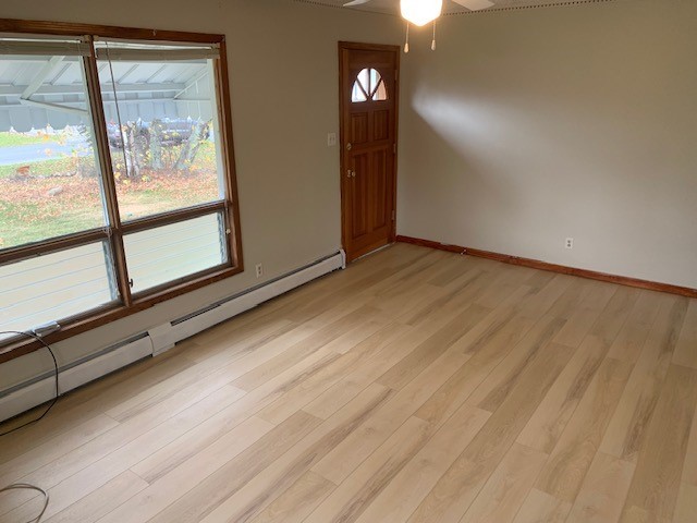 entrance foyer featuring ceiling fan, a baseboard radiator, and light wood-type flooring