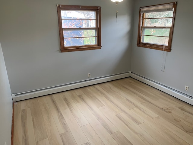 empty room with light hardwood / wood-style floors, baseboard heating, and a wealth of natural light