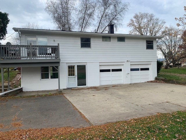 back of property with a wooden deck and a garage