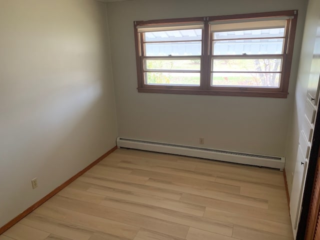 empty room with light hardwood / wood-style flooring and a baseboard radiator