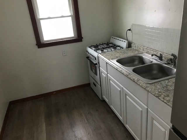 kitchen featuring dark hardwood / wood-style flooring, tasteful backsplash, gas range gas stove, sink, and white cabinetry