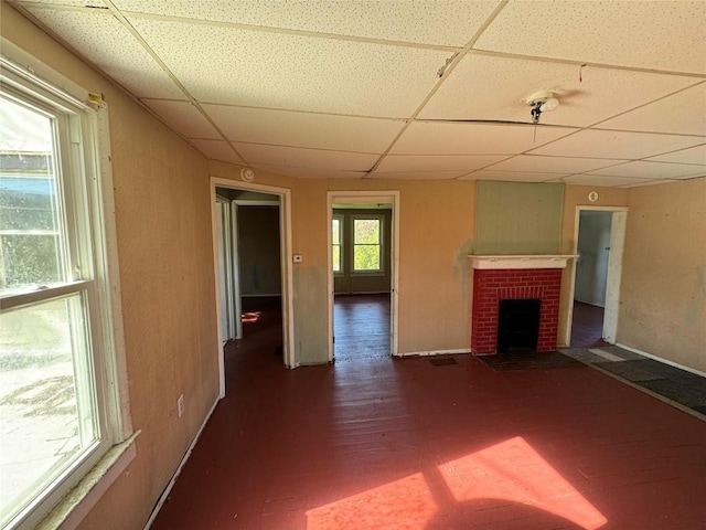 unfurnished living room with a paneled ceiling and a brick fireplace