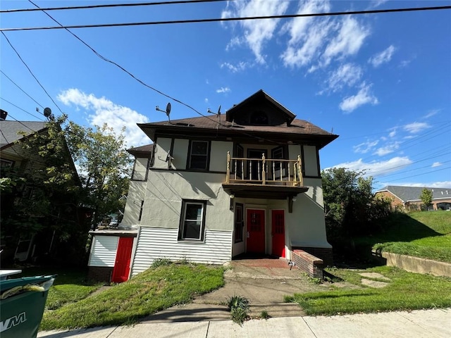 view of front of property featuring a balcony and a front lawn