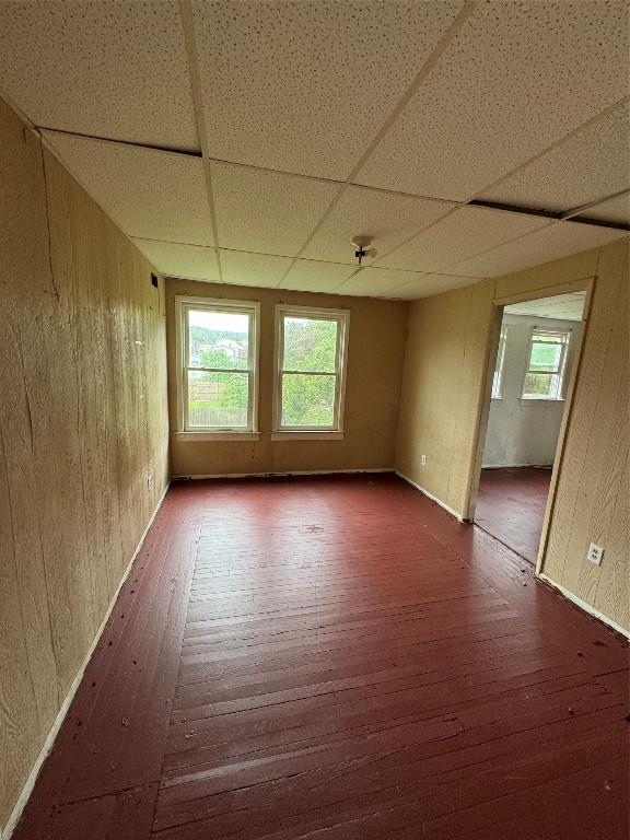 unfurnished room featuring a paneled ceiling, plenty of natural light, and dark hardwood / wood-style floors