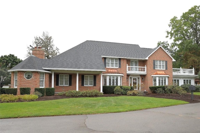 view of front of house with a balcony and a front yard