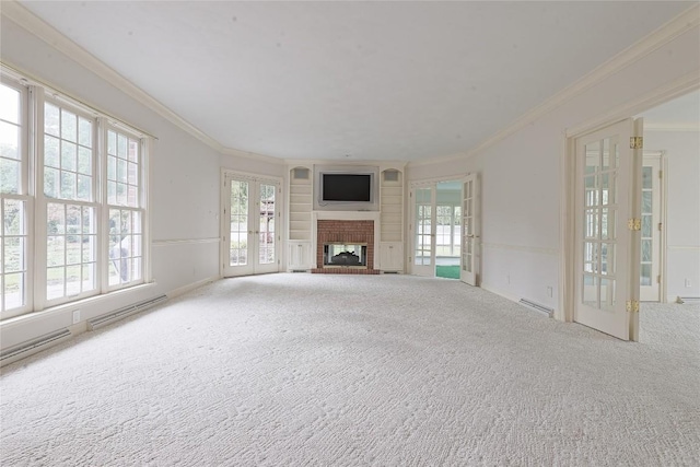 unfurnished living room featuring french doors, a brick fireplace, crown molding, and a healthy amount of sunlight