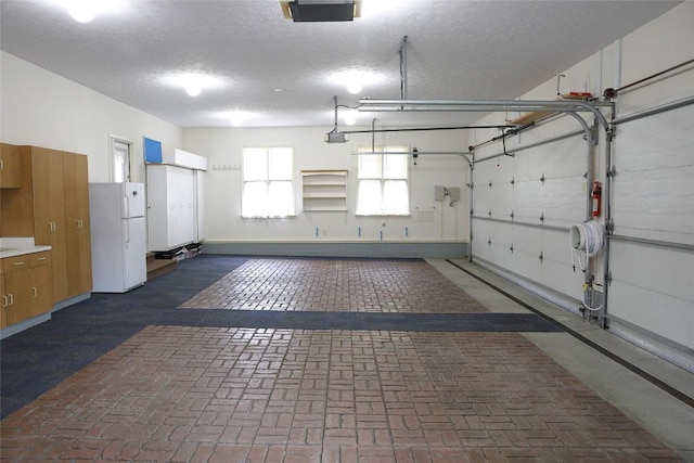 garage featuring white fridge and a garage door opener