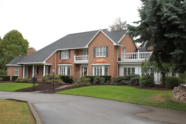 colonial house with a balcony and a front lawn