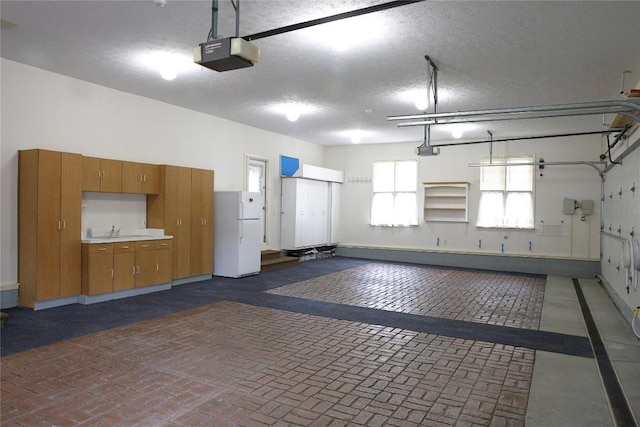 garage featuring white fridge, sink, and a garage door opener