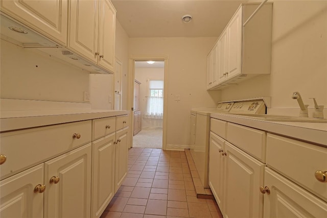 kitchen featuring washing machine and clothes dryer, white cabinetry, sink, and light tile patterned flooring