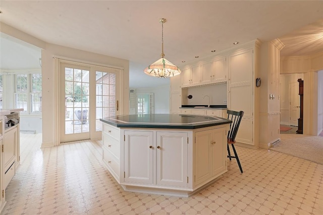 kitchen with white cabinetry, stovetop, a chandelier, decorative light fixtures, and a kitchen island