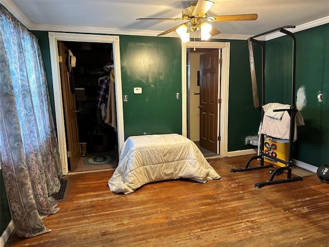 bedroom featuring ornamental molding, ceiling fan, baseboards, and wood finished floors