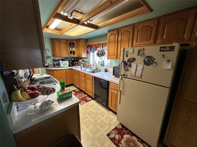 kitchen with dishwasher, freestanding refrigerator, light countertops, light floors, and a sink