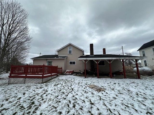 snow covered rear of property with a chimney and a deck