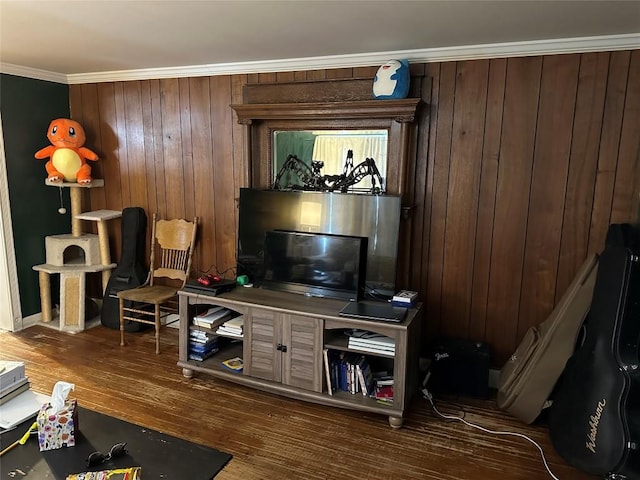 living room with ornamental molding, wooden walls, and wood finished floors