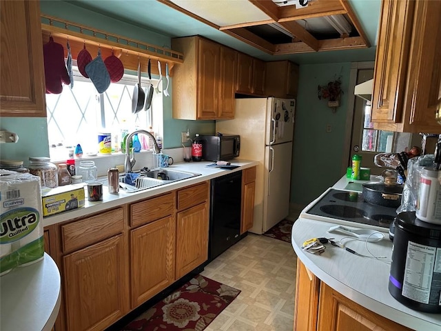 kitchen featuring brown cabinets, light floors, light countertops, black appliances, and a sink