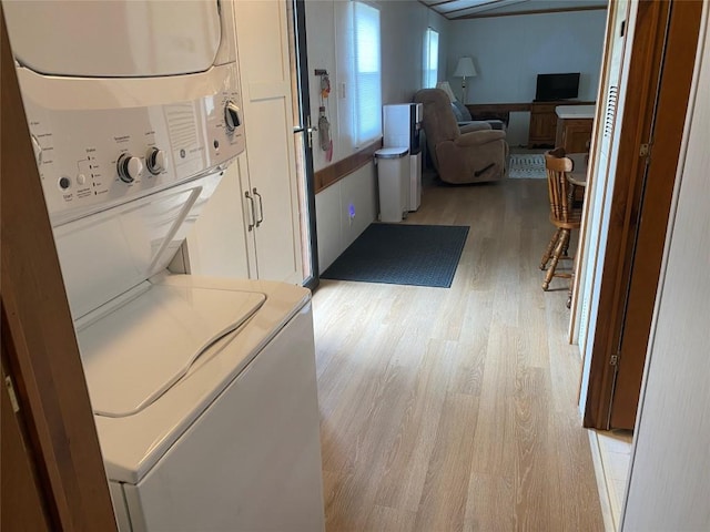 laundry area with stacked washer and dryer and light wood-type flooring