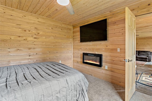 2629 River Dr, Jamestown, PA 16134 - carpeted bedroom with wood walls, wooden ceiling, a glass covered fireplace, and a ceiling fan
