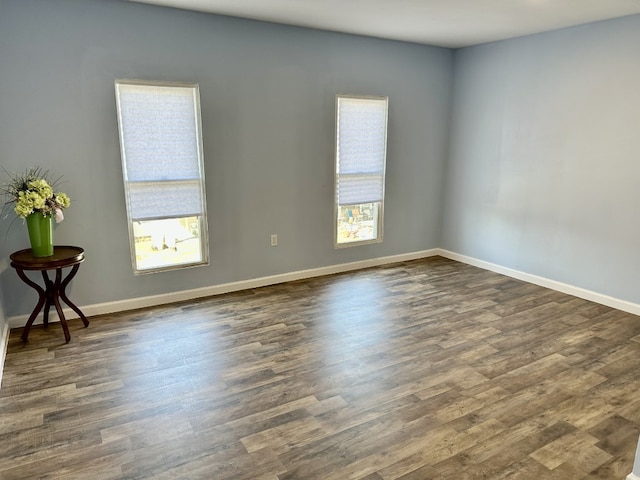 spare room with baseboards, a healthy amount of sunlight, and dark wood-style flooring