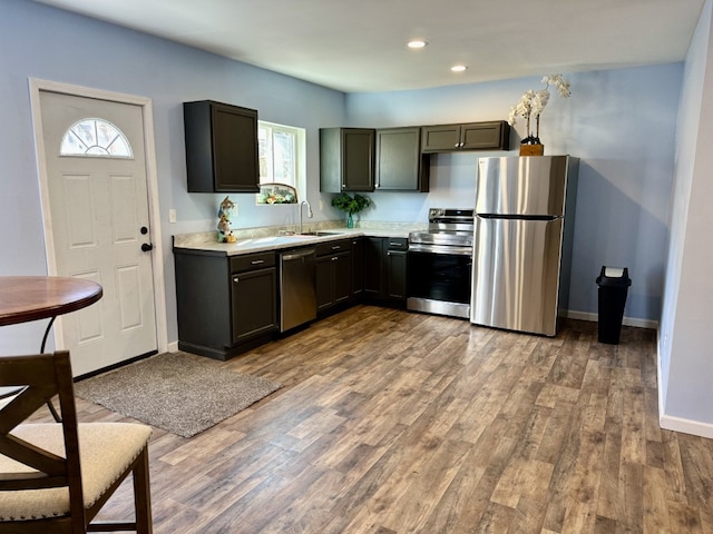 kitchen with appliances with stainless steel finishes, wood finished floors, light countertops, and a sink