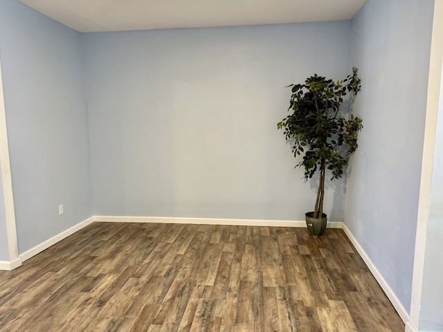 empty room featuring baseboards and dark wood finished floors