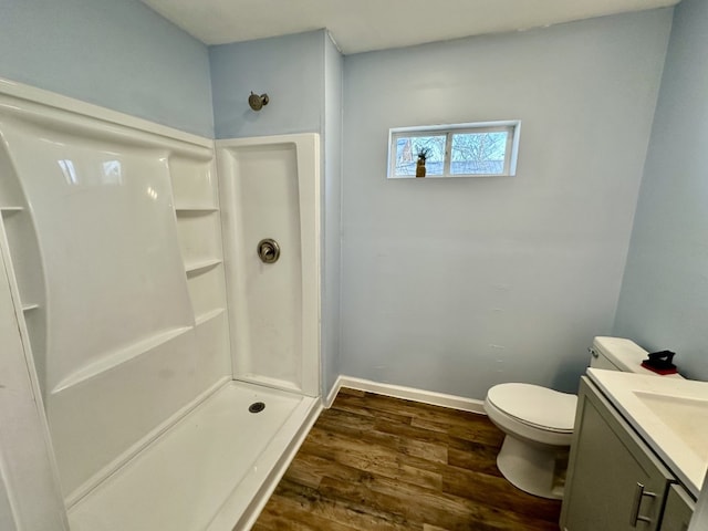 full bathroom featuring vanity, wood finished floors, baseboards, a shower stall, and toilet