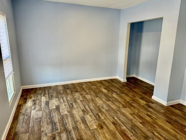 empty room with baseboards and dark wood-style floors