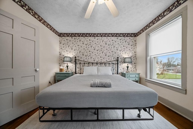 bedroom with ceiling fan, dark hardwood / wood-style flooring, and a textured ceiling