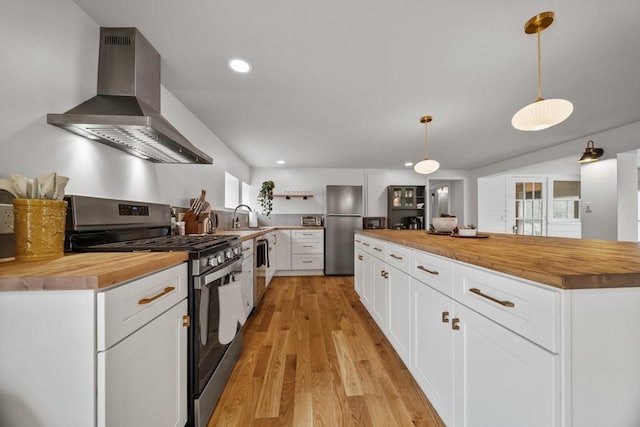 kitchen featuring stainless steel appliances, hanging light fixtures, white cabinets, and wooden counters